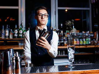barman at work. A young bartender works with a shaker. Prepares delicious alcoholic cocktails