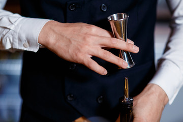 elegant young male barman prepares a delicious cocktail at the bar