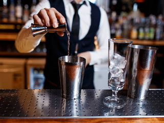 elegant young male barman prepares a delicious cocktail at the bar