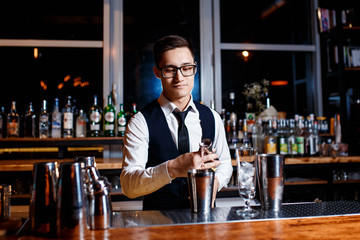 elegant young male barman prepares a delicious cocktail at the bar