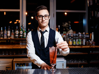 The bartender prepares a delicious orange cocktail with citrus. bartender at work