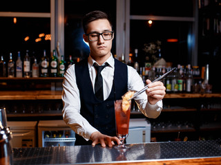 The bartender prepares a delicious orange cocktail with citrus. bartender at work