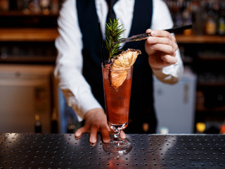 The bartender prepares a delicious orange cocktail with citrus. bartender at work