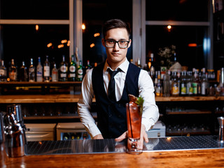 The bartender prepares a delicious orange cocktail with citrus. bartender at work
