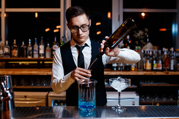 The bartender prepares a cool blue lagoon cocktail. Barman at work