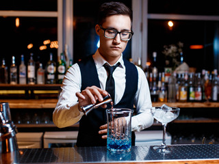 The bartender prepares a cool blue lagoon cocktail. Barman at work