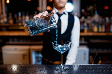 The bartender prepares a cool blue lagoon cocktail. Barman at work