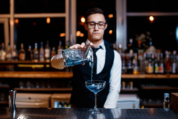 The bartender prepares a cool blue lagoon cocktail. Barman at work