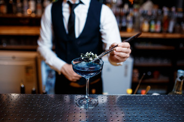 The bartender prepares a cool blue lagoon cocktail. Barman at work