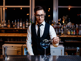 The bartender prepares a cool blue lagoon cocktail. Barman at work