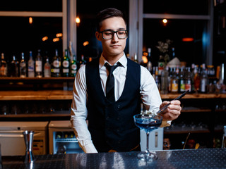 The bartender prepares a cool blue lagoon cocktail. Barman at work