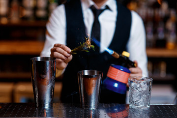 elegant young male bartender preparing a delicious cocktail at the bar. barman szmat razmarin gas torch