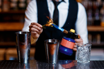 elegant young male bartender preparing a delicious cocktail at the bar. barman szmat razmarin gas torch