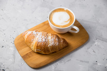 Beautiful and simple traditional French breakfast of fresh croissant and a cup of cappuccino