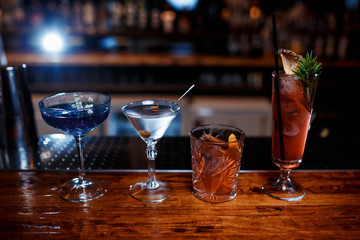 Different beautiful cocktails on a wooden bar counter. 4 alcoholic cocktails