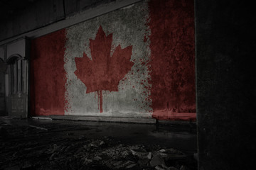 painted flag of canada on the dirty old wall in an abandoned ruined house.