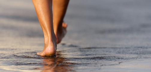 Barefoot woman walking in ocean water waves