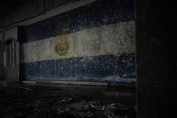 painted flag of el salvador on the dirty old wall in an abandoned ruined house.