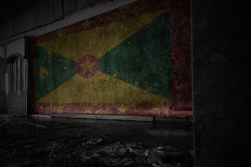 painted flag of grenada on the dirty old wall in an abandoned ruined house.