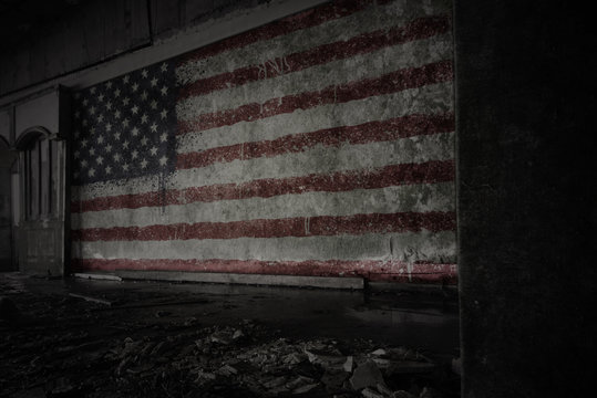 painted flag of united states of america on the dirty old wall in an abandoned ruined house.