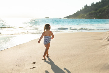 Fototapeta na wymiar Rear View Of A Toddler Girl Walking At Beach