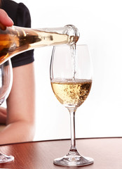 Champagne bottle in woman hands. Pouring fizzy into glass.