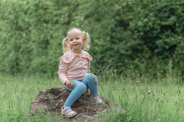 Little girl sitting on the stone and laughs