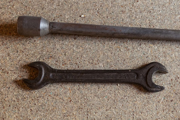 Hex key for car wheels and a wrench lie on a wooden surface, parallel horizontal tool