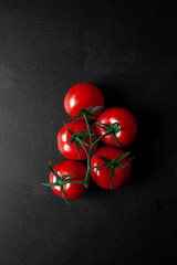 Red fresh organic tomatoes on isolated background with blue and white cloth. On gray natural black stone background.