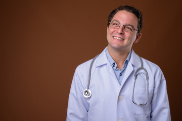 Portrait of Italian man doctor against brown background