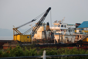 Fototapeta na wymiar Crane on the ship with other ship moored at the harbor in river.