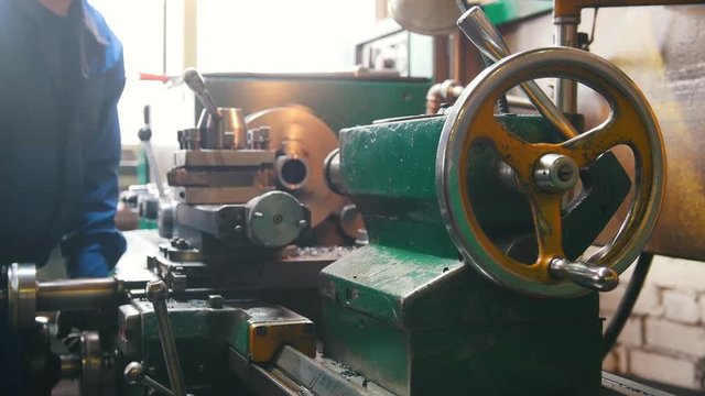 Industrial concept. Construction plant. A man working with a lathe - cut out the detail and remove it off the lathe