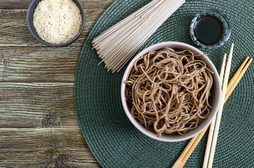 Cold soba (buckwheat noodles) with sauce and sesame. Japanese food. Traditional asian cuisine - noodles from buckwheat flour. Top view, flat lay. - obrazy, fototapety, plakaty