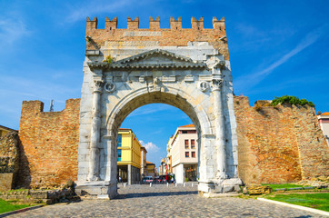 Ruins of ancient brick wall and stone gate Arch of Augustus Arco di Augusto and cobblestone road in...