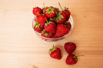 Beautiful, ripe red strawberries shot from above in a glass saucer on a worn white background.