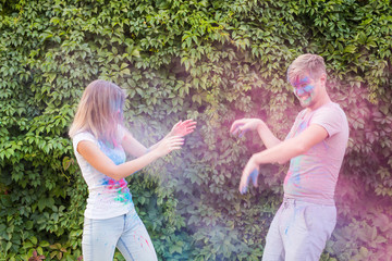 Obraz premium Holiday, holi and people concept - Happy couple having fun covered in paint