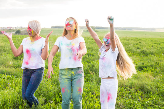 Holi festival, friendship, holidays and people concept - Jumping happy women and girls covered in paint