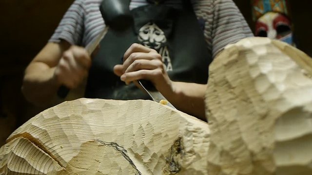 the sculptor carves a figure from a tree