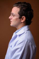 Italian man doctor wearing protective glasses against brown back