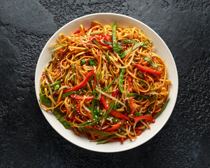 Chow mein, noodles and vegetables dish with wooden chopsticks