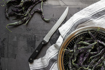 Green and black fresh organic sliced beans on isolated background with blue and white cloth and...