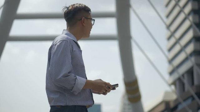 Slow motion portrait asian businessman texting with friend on smartphone at urban city background, Searching for social media.