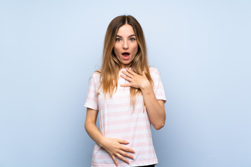 Young woman over isolated blue background surprised and shocked while looking right