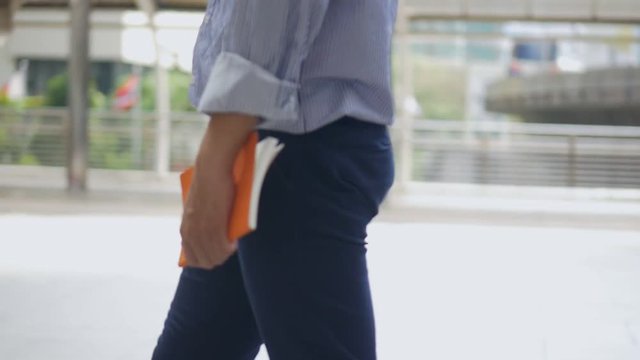Close up portrait caucasian businessman hand holding a book walking on the street urban city.