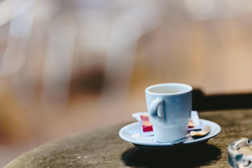 Empty white coffee cup on the wooden table of an outdoor bar, negative space for text.