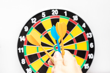 Obraz premium A hand holding a blue dart ready to throw it to a dartboard target, strategy and skill in business concept
