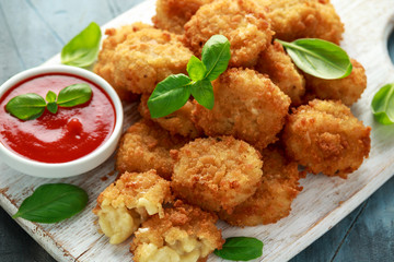 Fried Mac, macaroni and Cheese Bites in breadcrumbs with ketchup sauce on white wooden board