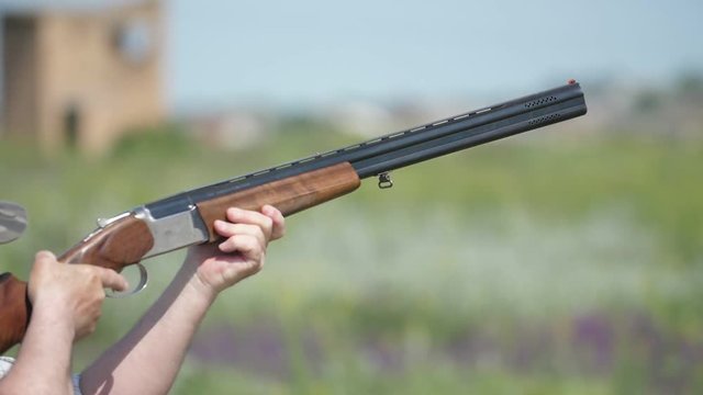 Man firing from over and under rifle practicing clay shooting in slow motion   
