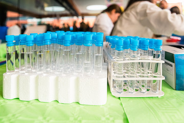 Many test tubes with blue plugs in a rack full of scientific experiments.