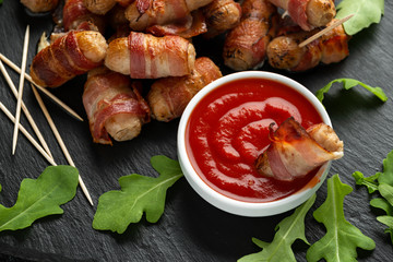 Party finger food pigs in blankets on toothpicks with ketchup sauce and wild rocket leaves